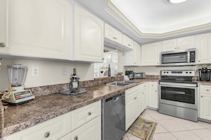 Eine moderne Küche mit weißen Schränken, einer Granit-Arbeitsplatte, einem Backofen, einer Mikrowelle und einem Geschirrspüler.