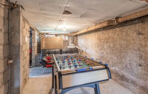 A room with a foosball table, a brick wall, and a ceiling with exposed pipes. - Awesome home in Lézardrieux with WiFi (Lézardrieux)