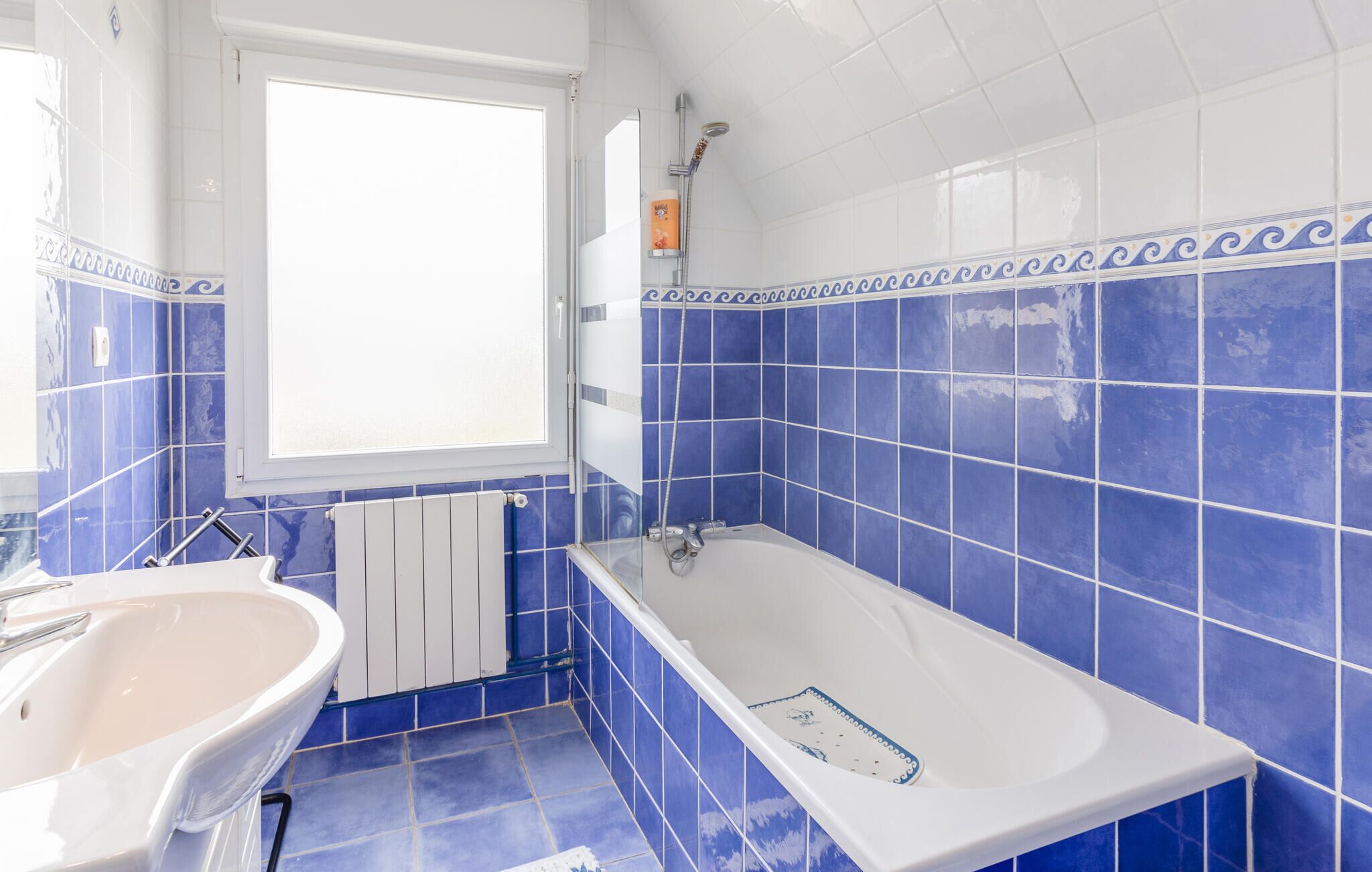A bathroom with a bathtub, a sink, and a window.