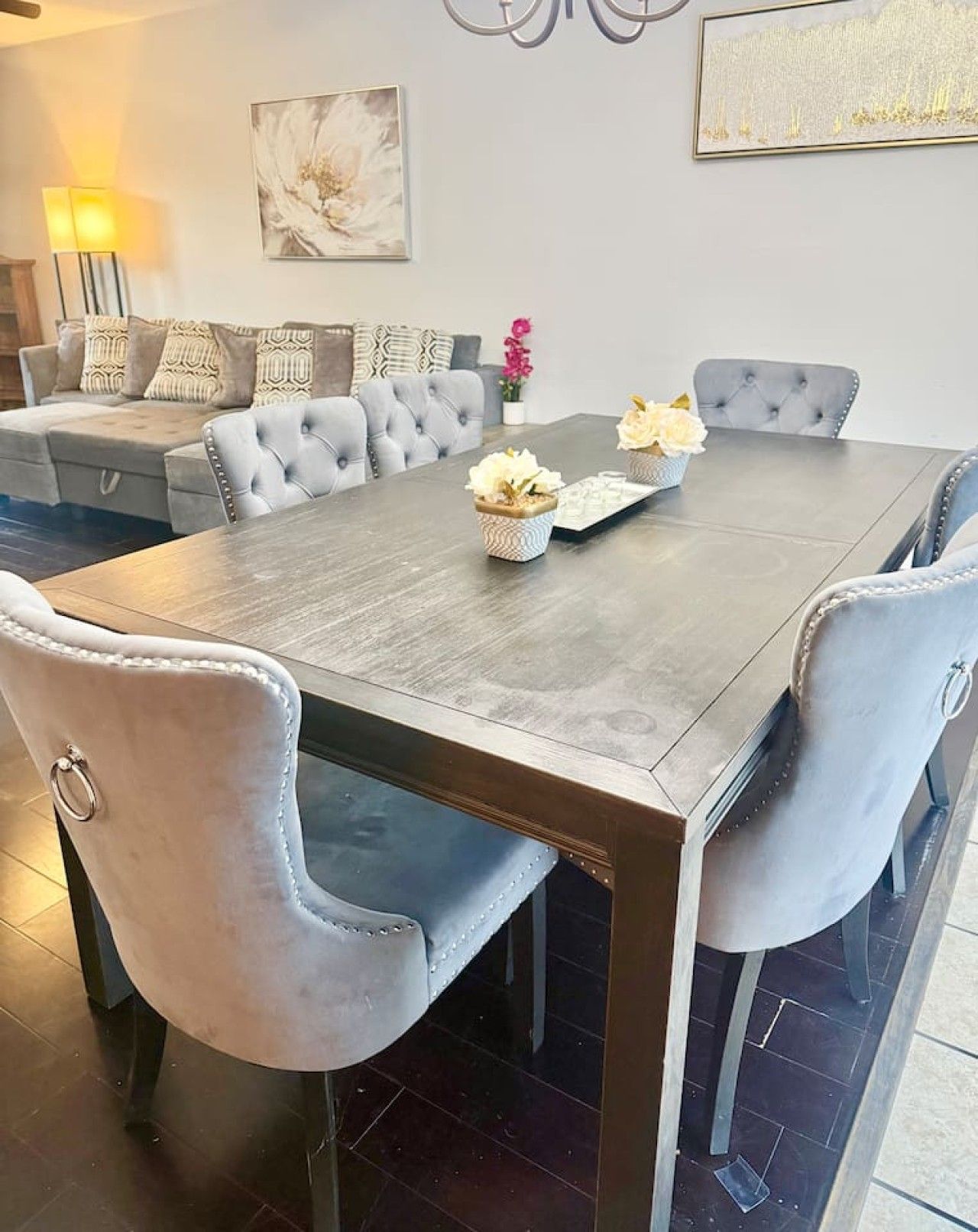 Un comedor con una mesa rectangular, sillas tapizadas en gris y un centro de mesa decorativo.
