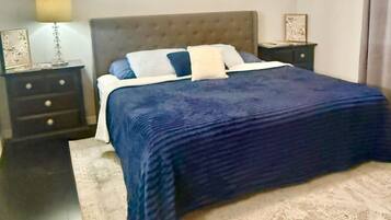 Un dormitorio con cama, mesitas de noche, lámpara y alfombra.