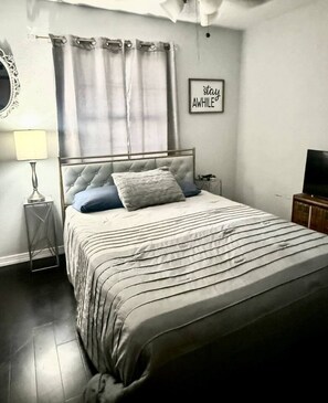 A bedroom with a bed, a nightstand, a lamp, a television, and a wall with a framed quote. - Terrific 3 BR home in The Colony, Frisco and Plano (The Colony)
