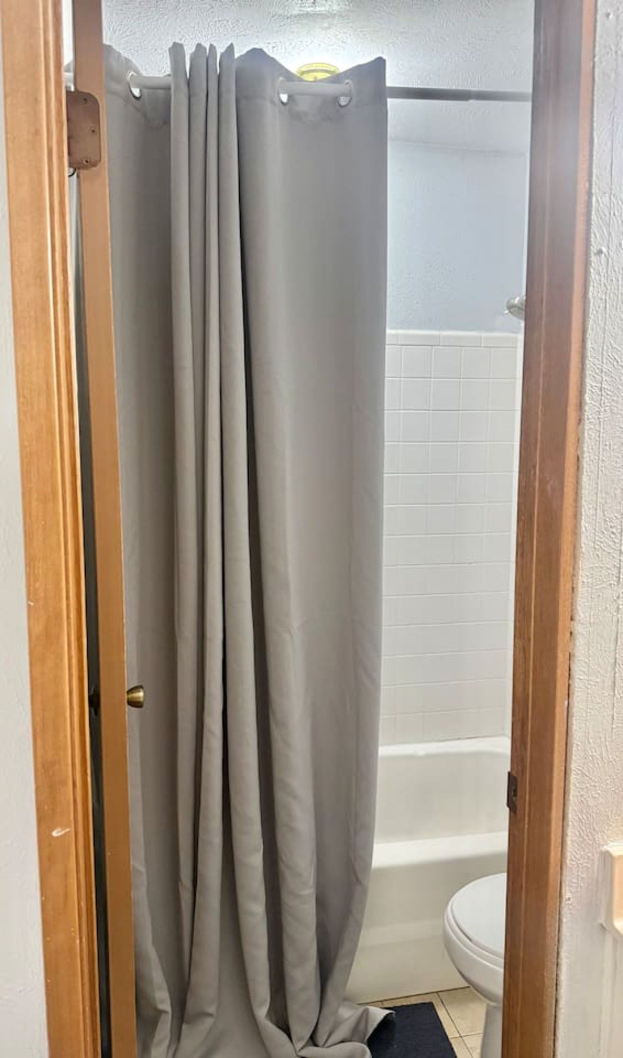 A bathroom with a shower curtain, a toilet, and a tiled wall.