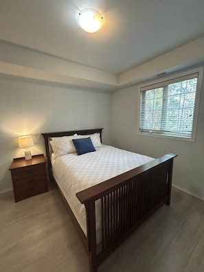 A bedroom with a bed, a nightstand, a window with blinds, and a ceiling light. - Spacious 3BR Condo with Pool, Hot Tub & Golf Views - 2110 (Kelowna)