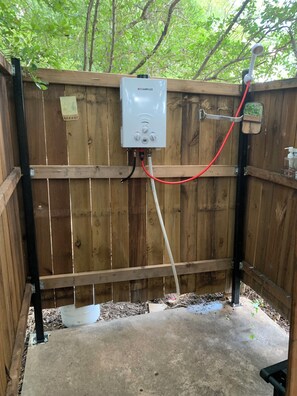 A portable water heater mounted on a wooden fence with a hose connected to it. -     Gypsy Mini Charming Tiny Cabin at Red Canoe Lodge with Resort Amenities (Clifton)