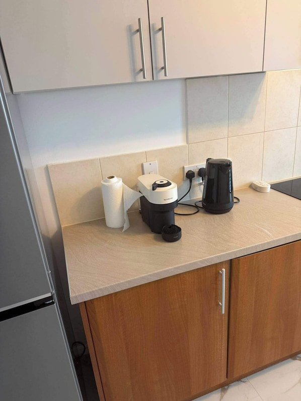 A kitchen with a coffee machine, a roll of paper towels, and a kettle on the counter.
