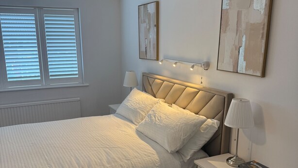 A bedroom with a bed, bedside tables, a lamp, and artwork on the wall. - Apartment Sleeps 6 with Parking (Stanmore)