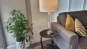 A modern living room with a grey sofa, a potted plant, and a table lamp. - Cozy Central London, Zone 1 Apartment, sleeps 5 (London)