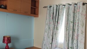 A bedroom with two beds, a desk, a lamp, and a wardrobe.