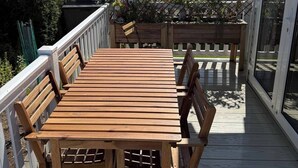 A wooden deck with a table and chairs, surrounded by a white railing, and a glass door leading to a covered area. - 2 x Cabin Retreat in Coldingham (Coldingham)