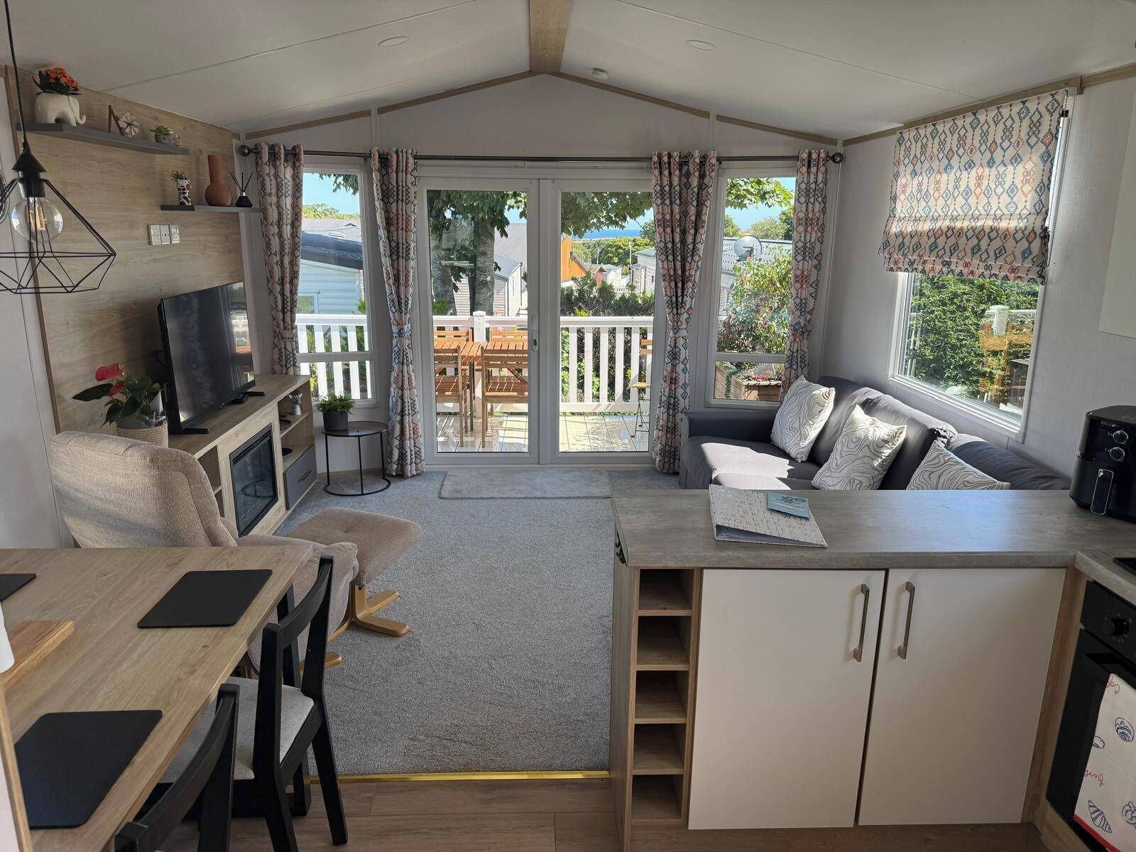 A compact living space with a kitchenette, a seating area with a sofa, a dining table, and a TV.