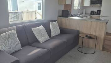 A modern living room with a grey sofa, patterned cushions, and a small round table.