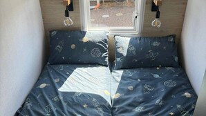 A bed with a space-themed duvet and pillows, a window with a patterned blind, and two wall-mounted light fixtures. - 2 x Cabin Retreat in Coldingham (Coldingham)