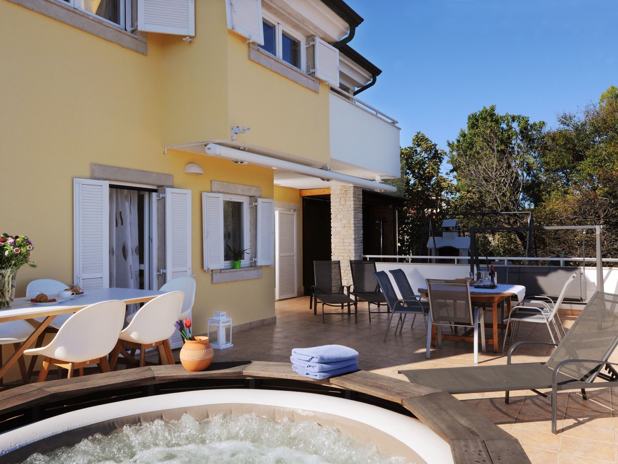 Ein Wohnhaus mit einer Terrassenanlage, Sitzgelegenheiten im Freien und einem Whirlpool.