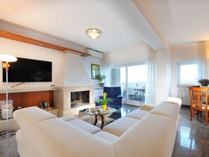 Una sala de estar moderna con un televisor de pantalla plana, chimenea, sofá y comedor con mesa y sillas.