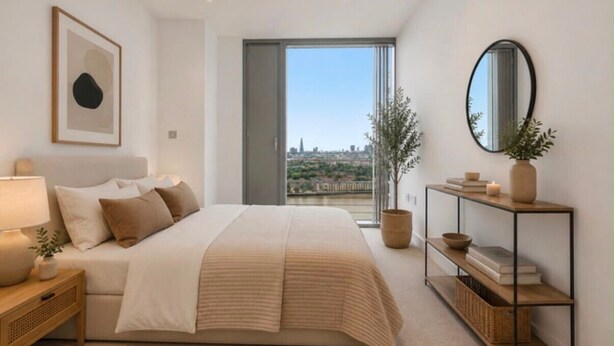 Ein Schlafzimmer mit einem Bett, Nachttisch und einer Aussicht auf die Stadt durch ein großes Fenster.