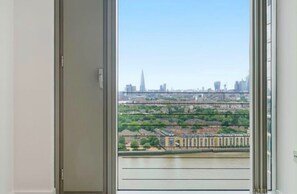 Vista pela janela de um horizonte urbano com edifícios, um rio e uma ponte.