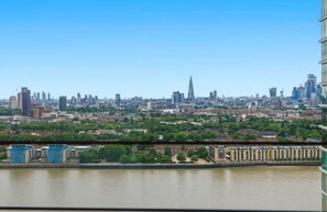 A cityscape with a river, modern buildings, and a prominent tower. - Canary Wharf Skyline Retreat (London)