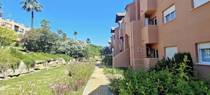 A residential building with a paved pathway, greenery, and palm trees. - House Sleeps 6 with Indoor Pool and Parking (Casares , CASARES DEL SOL)