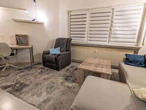A living room with a dark armchair, a small wooden table, a white sofa, a rug, and a window with blinds. - im Anbau by Interhome (Frammersbach)