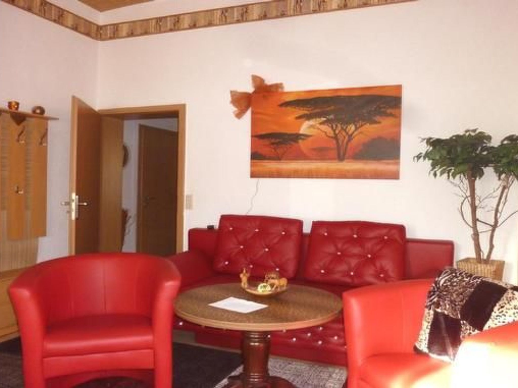 Ein Zimmer mit einem roten Sofa, einem roten Sessel und einem kleinen runden Tisch mit einem dekorativen Gegenstand.