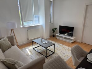 Ein modernes Wohnzimmer mit Sofa, Couchtisch und einem Flachbildfernseher auf einem Lowboard.