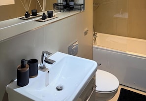 A bathroom with a white sink, a toilet, and a shower area. - Executive 1 Bedroom Apartment- East Croydon (Croydon)