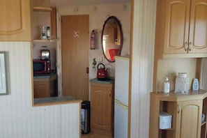 A compact kitchen with a microwave, kettle, and a small refrigerator.