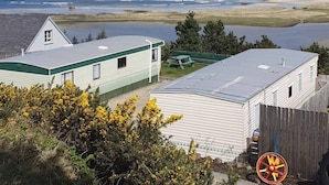 A coastal view with a house and a trailer, a sandy beach, and the ocean. - Donegal Coastal Mobile Homes with Private Garden (Letterkenny)