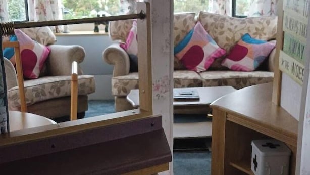 A room with a sofa, a small table, and a mirror reflecting the room. - Donegal Coastal Mobile Homes with Private Garden (Letterkenny)