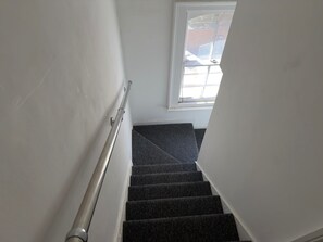 Eine Treppe mit Geländer, Teppichstufen und einem Fenster mit Ausblick.
