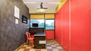 A room with a checkered floor, a desk with a computer, a chair, a wall calendar, and a window with a view of buildings. - Collection O Eco Park Kolkata (Barasat)