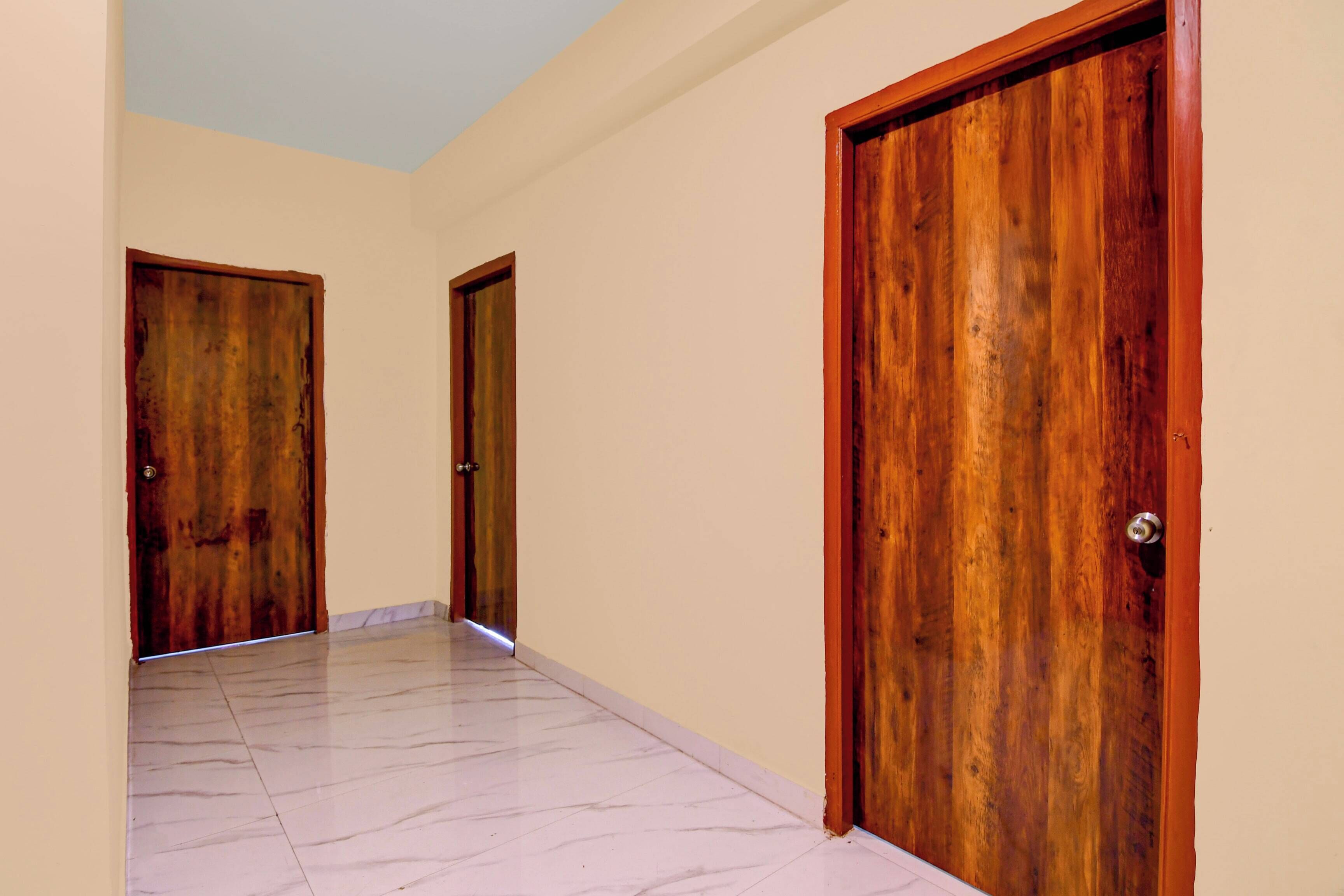 Un pasillo con dos puertas de madera y piso de baldosas.