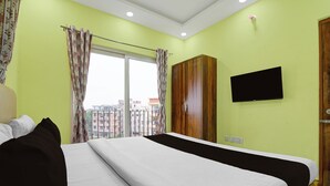 A hotel room with a bed, a wardrobe, a television, and a window with curtains. - Collection O Eco Park Kolkata (Barasat)