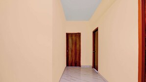 A hallway with marble flooring and two wooden doors. - Collection O Eco Park Kolkata (Barasat)