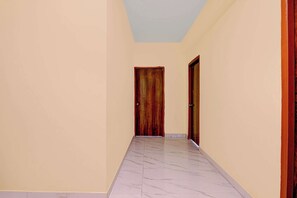 A hallway with marble flooring and two wooden doors.