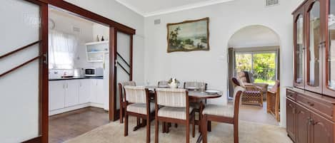 A dining area with a round table, chairs, and a painting on the wall.