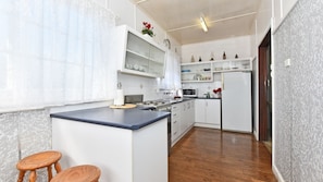 A compact kitchen with a central island, wooden stools, and a microwave. - Morpeth Cottage | In the hear of Morpeth (Morpeth)
