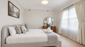 A bedroom with a bed, pillows, a bedside table, a mirror, and a window with curtains. - Morpeth Cottage | In the hear of Morpeth (Morpeth)