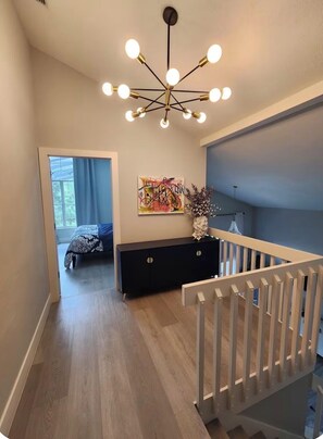 Ein modernes Interieur mit Treppe, einem Bett, einer schwarzen Konsole und einer Deckenleuchte.