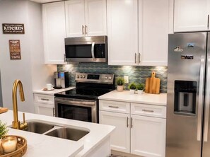Eine moderne Küche mit weißen Schränken, Edelstahlgeräten und einer gefliesten Spritzschutzwand.