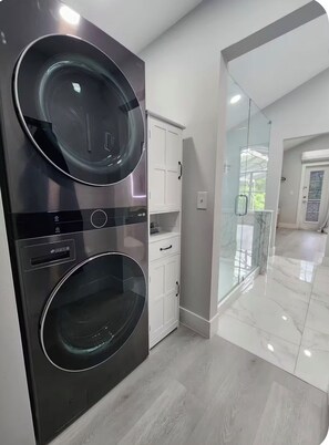 Eine moderne Küche mit Backofen, weißen Schränken und einer Glastür zu einem hellen Raum.