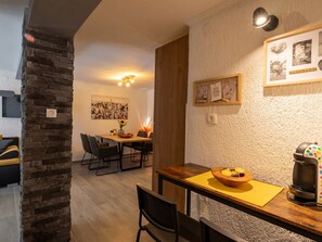 Ein gemütlicher Essbereich mit Holztisch, Stühlen und einer Kaffeemaschine.