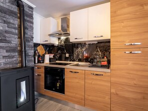 Una cocina moderna con estufa integrada, armarios de madera y salpicadero de mármol.