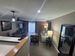 Une chambre d’hôtel comprenant un coin repas, un canapé, une télévision et une lampe.