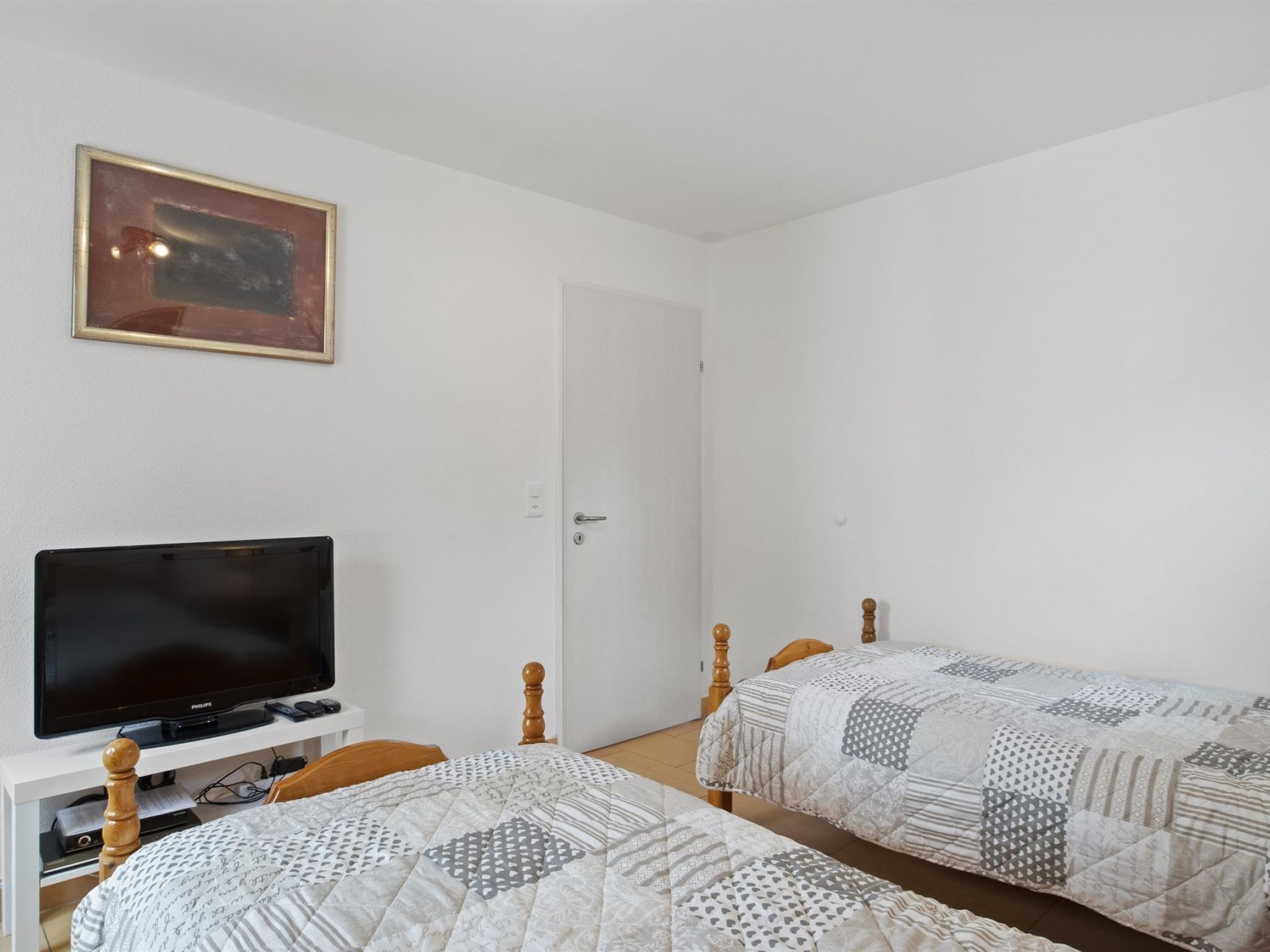 Una habitación con dos camas individuales, una televisión y una puerta.