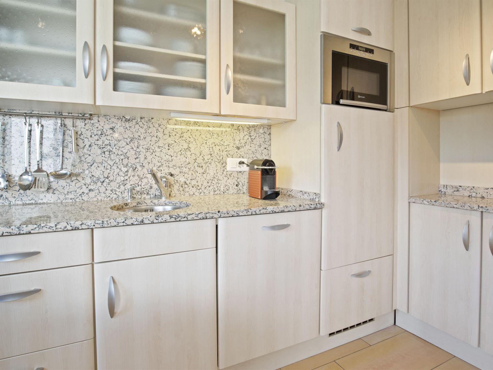 A kitchen with a granite countertop, stainless steel appliances, and white cabinetry.