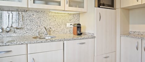 Cocina con encimera de granito, electrodomésticos de acero inoxidable y muebles de cocina blancos.
