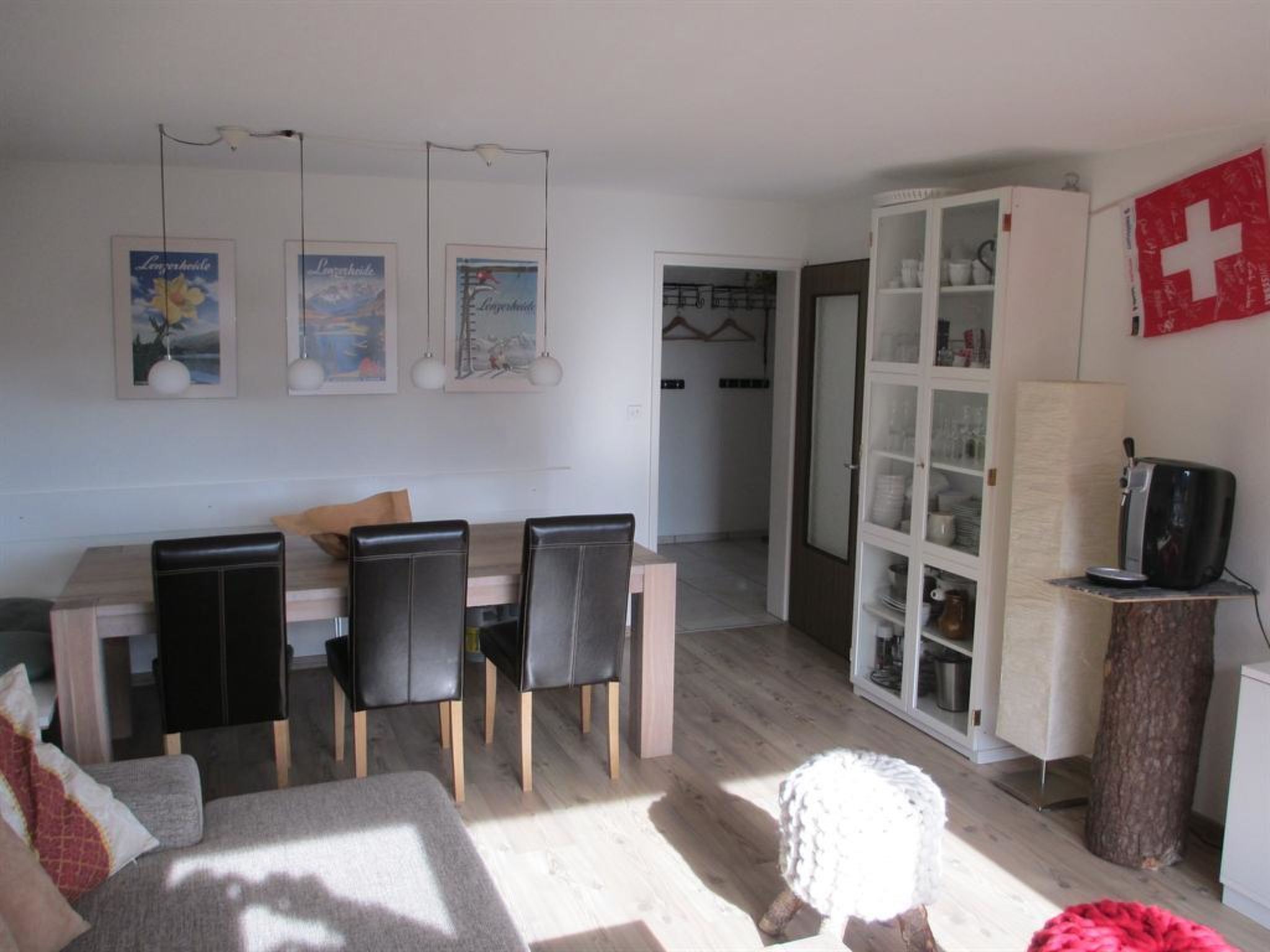 A modern living room with a dining area, a kitchen, and a visible door leading to another room.
