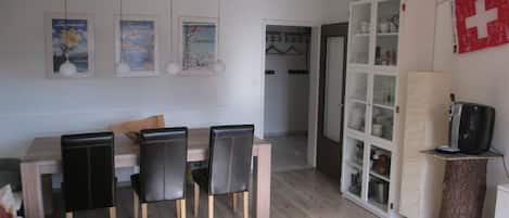 A modern living room with a dining area, a kitchen, and a visible door leading to another room.